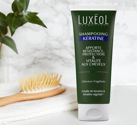 Luxéol šampūnas su keratinu, nufotografuotas šalia šepečio ir rankšluosčio, naudoti 2–3 kartus per savaitę, derinti su Kaukė su keratinu.