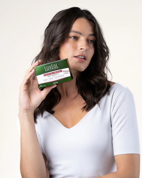 Moteris, laikanti Luxéol produkto dėžutę baltame fone