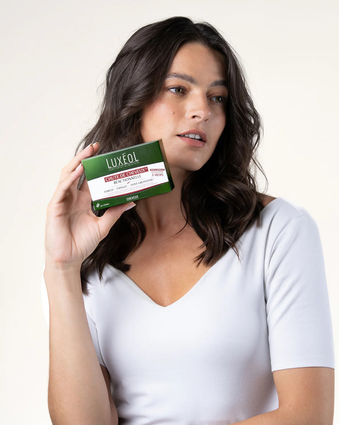 Moteris, laikanti Luxéol produkto dėžutę baltame fone