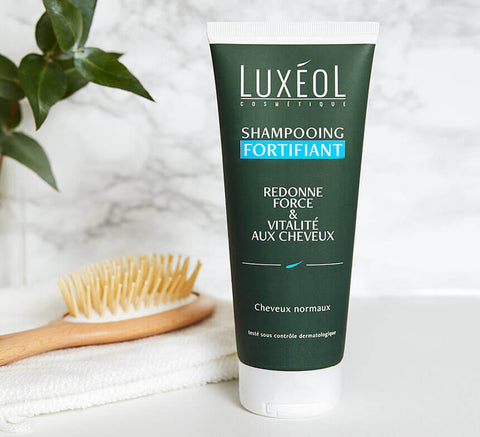 Stiprinamasis šampūnas, šalia šepetys ir rankšluostis; naudokite 2–3 kartus per savaitę, įmasažuokite, gerai nuskalaukite.