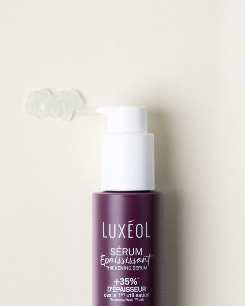 Luxéol serumo buteliukas su pompa ant smėlio spalvos fono